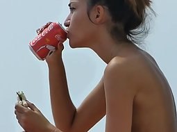 Topless girl eating at the beach